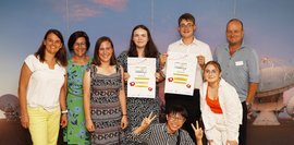 Eine Gruppe Schüler, die Plakate in der Hand halten und mit drei Erwachsenen für ein Foto posieren