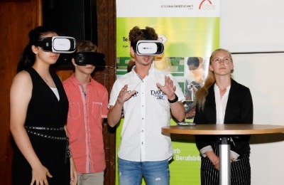 Eine Schülerin schaut nach oben und steht neben einer Gruppe von zwei Jungs und einem Mädchen, alle drei tragen eine Virtual Reality Brille