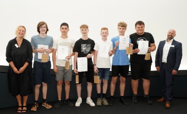 Sechs Schüler, die Plakate in der Hand halten und mit zwei Erwachsenen für ein Foto posieren