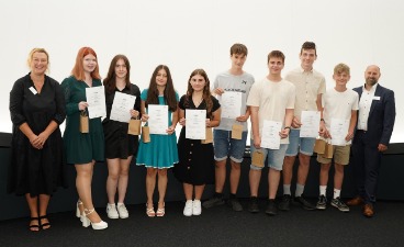 Eine Gruppe von Schülern, die Plakate in der Hand halten und mit zwei Erwachsenen für ein Foto posieren