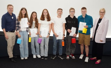 Die Gewinner des Zukunftspreises Drei Schülerinnen und drei Schüler, die Plakate in der Hand halten und mit zwei Erwachsenen für ein Foto posieren